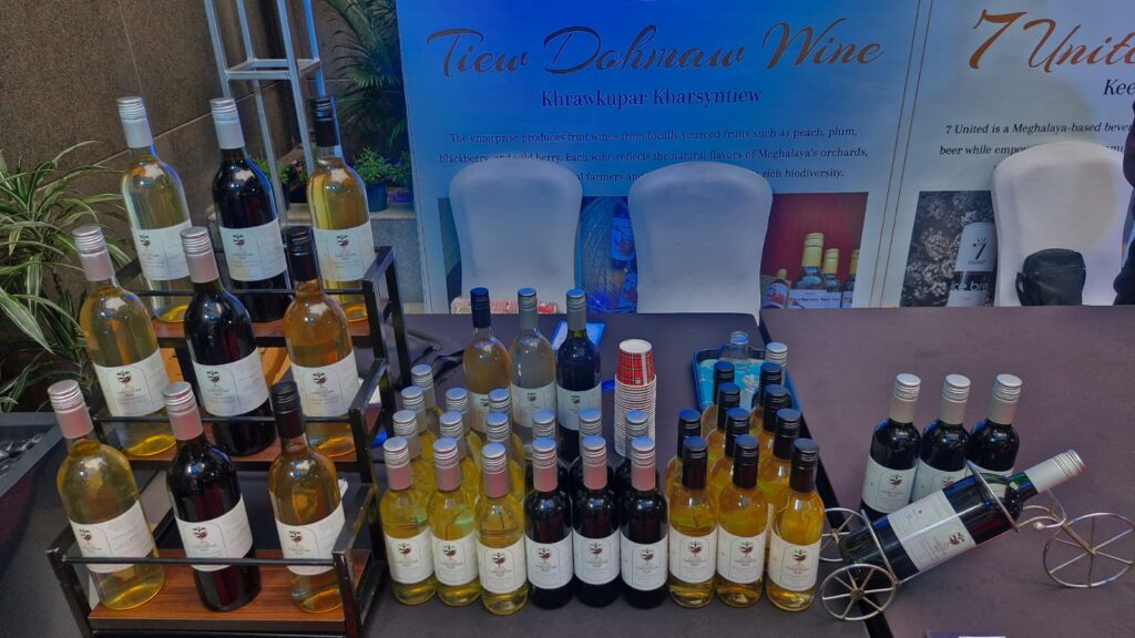 Tiewdohmaw organic fruit wines from Meghalaya — handcrafted red and white bottles displayed with wine glasses at trade event.
 Handcrafted, Naturally Fermented
