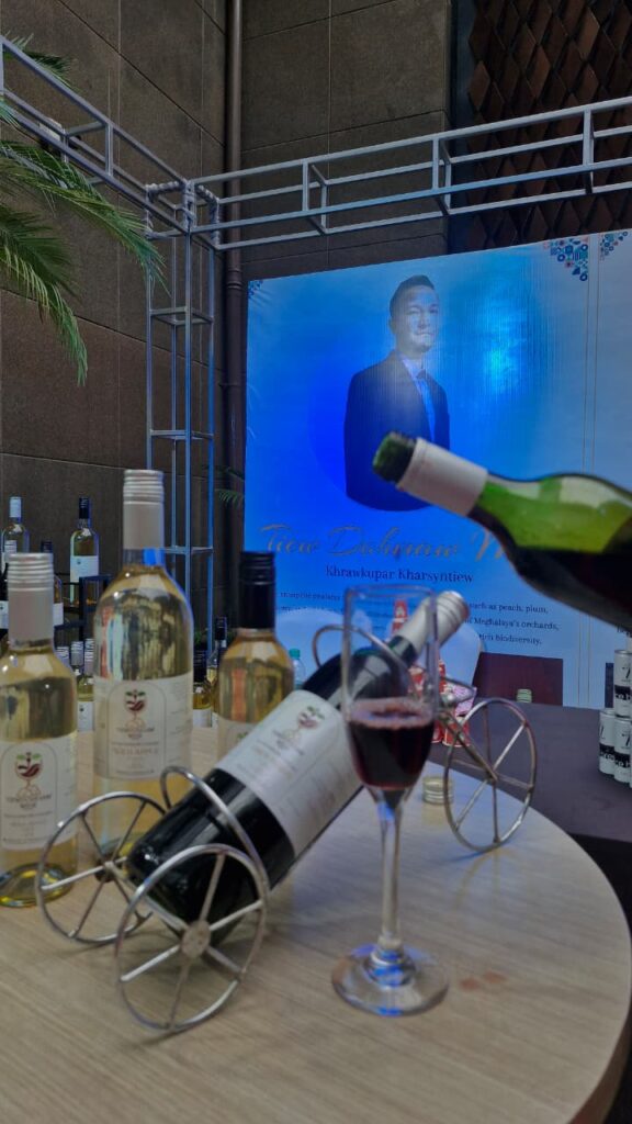 Tiewdohmaw organic fruit wines from Meghalaya — handcrafted red and white bottles displayed with wine glasses at trade event.